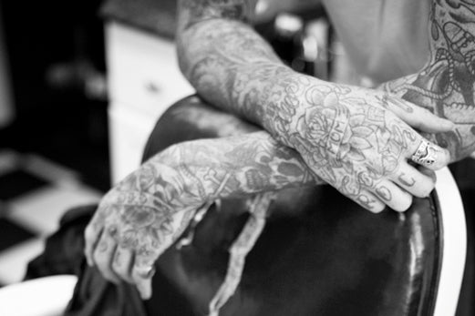 Tätowierter Friseur lehnt am Stuhl